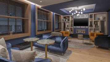 A modern living room with blue sofas, round tables, and a TV wall unit.
