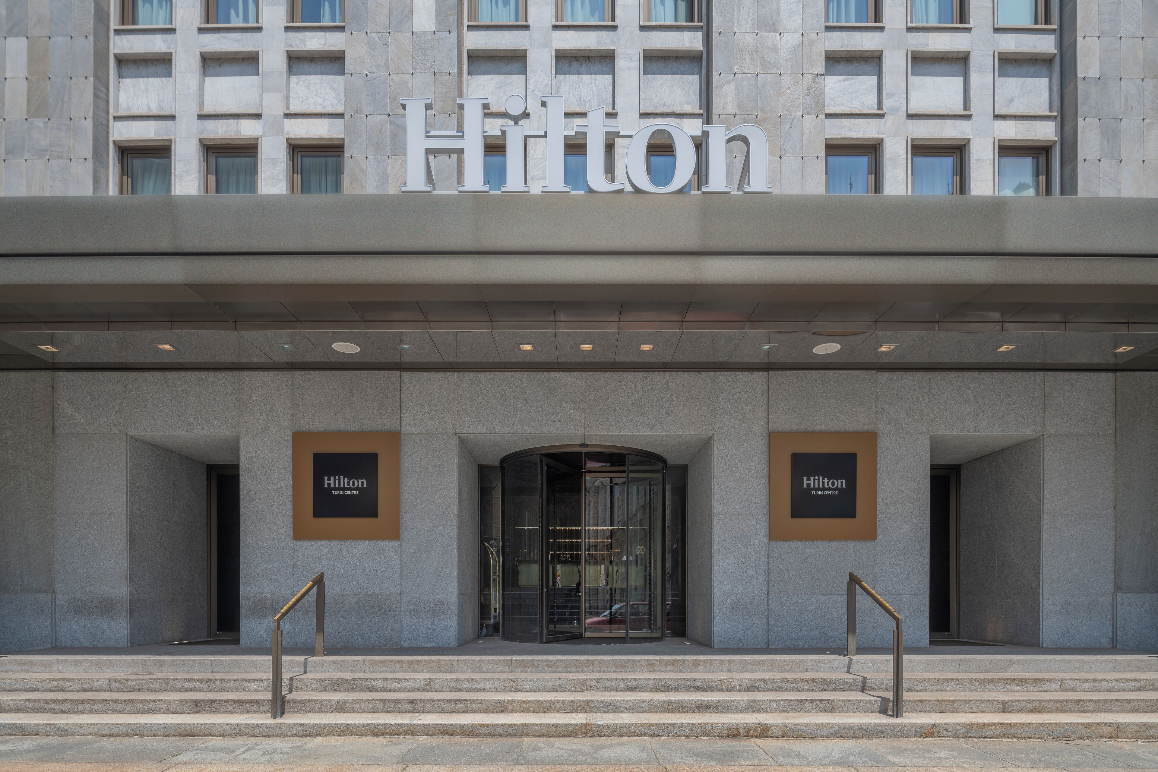A modern hotel entrance with a large sign reading "Hilton" above the doors.