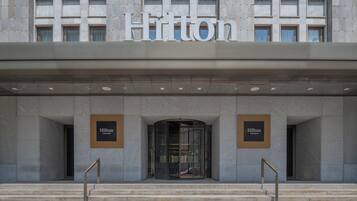 Ein moderner Hotelzugang mit einem großen Schild, auf dem "Hilton" über der Tür steht.