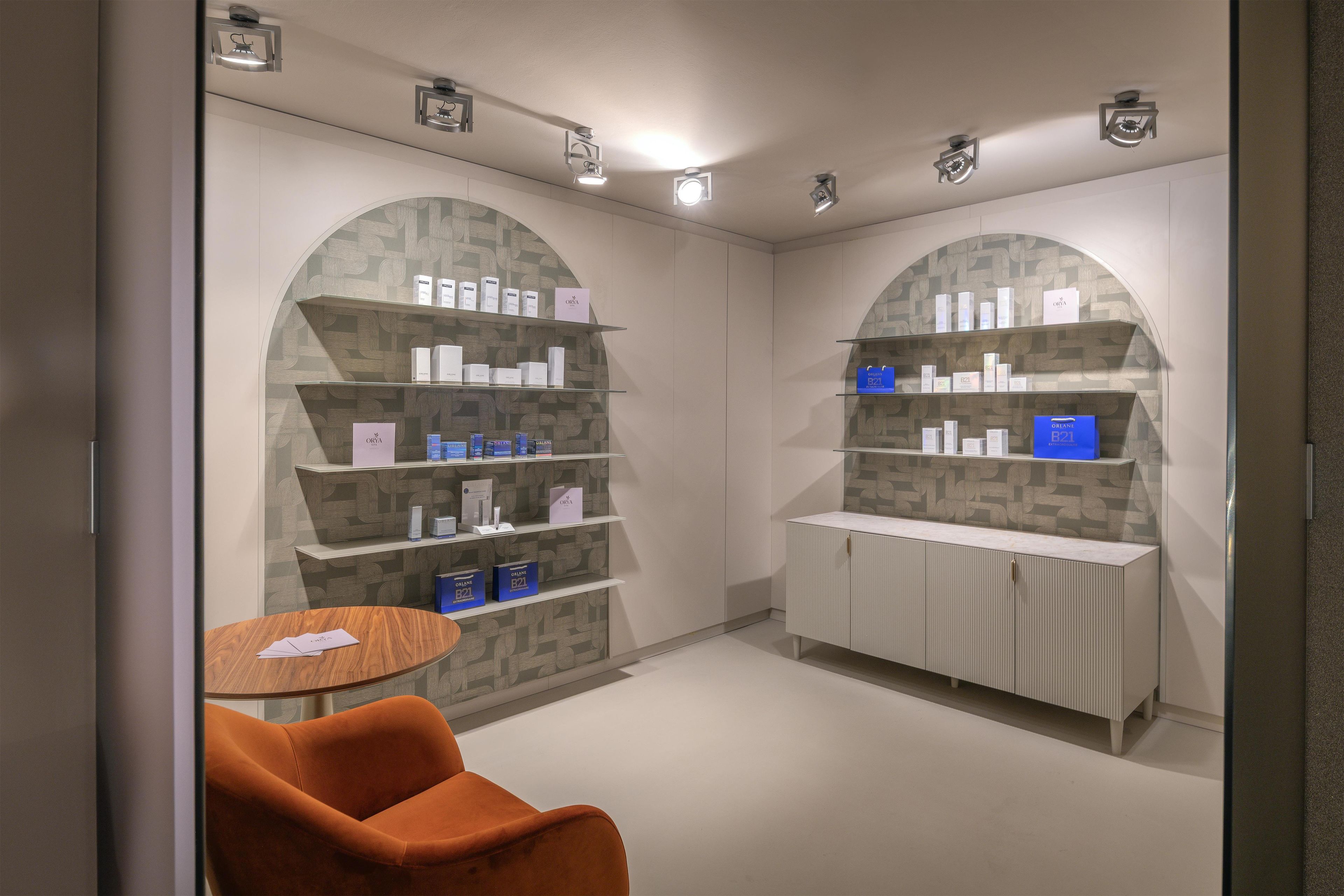 A modern, well-lit room with arched shelving displaying various products, a round table with a chair, and a minimalist design.