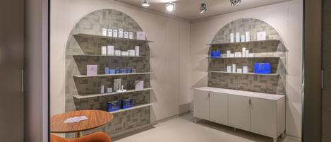 A modern, well-lit room with arched shelving displaying various products, a round table with a chair, and a minimalist design.