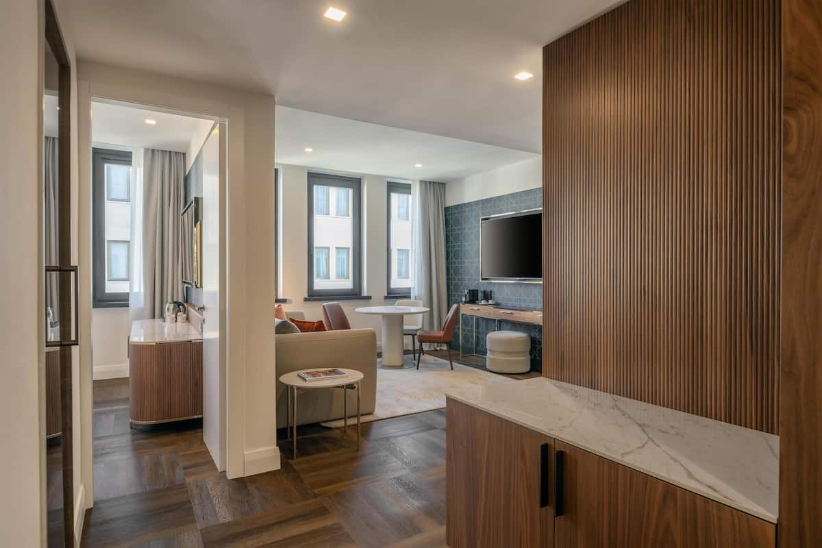 A modern kitchen with wooden cabinets, a marble countertop, and a dining area with a white table and chairs.