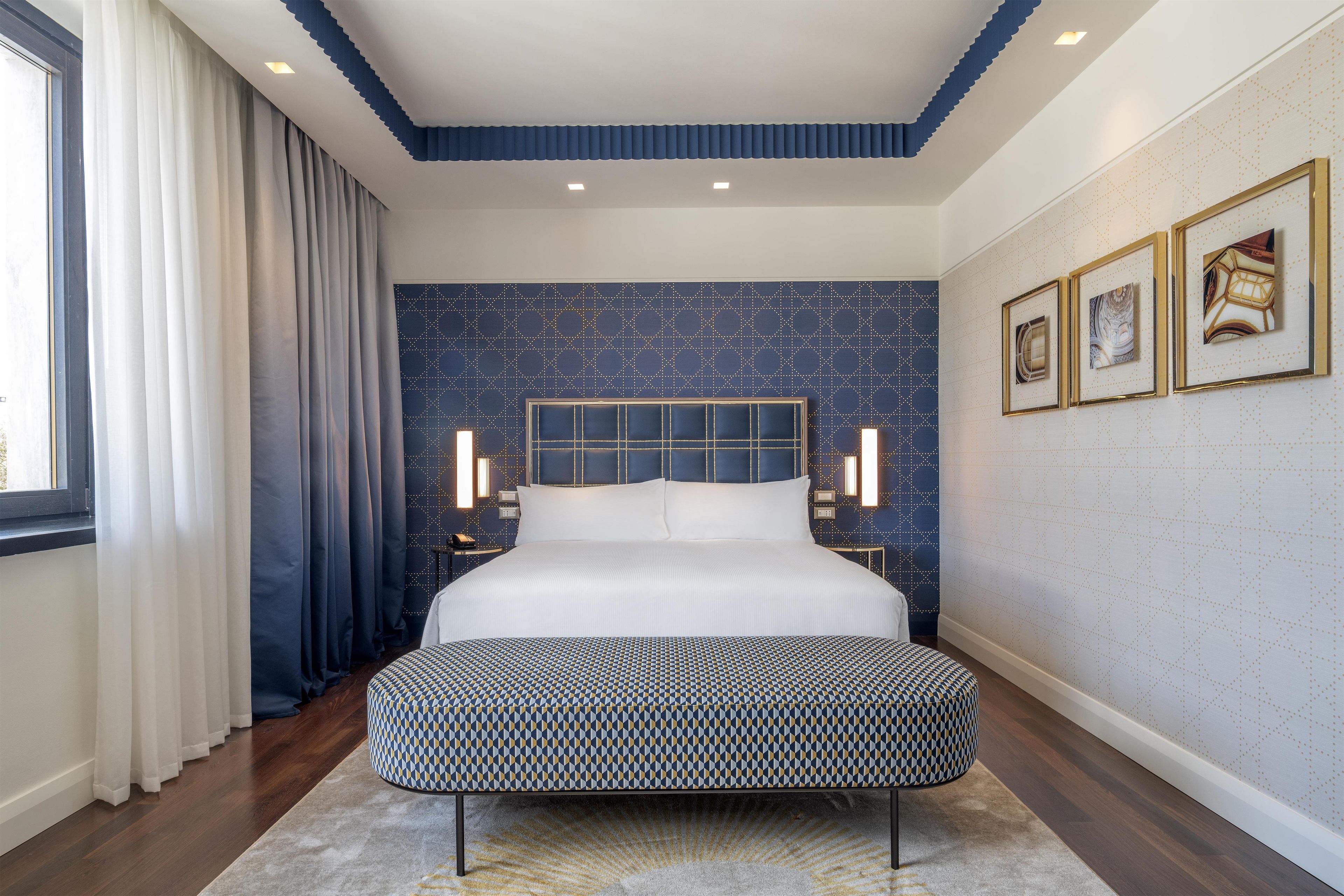 Ein modernes Schlafzimmer mit einem großen Bett, einer Bank und einer Wand mit Muster.