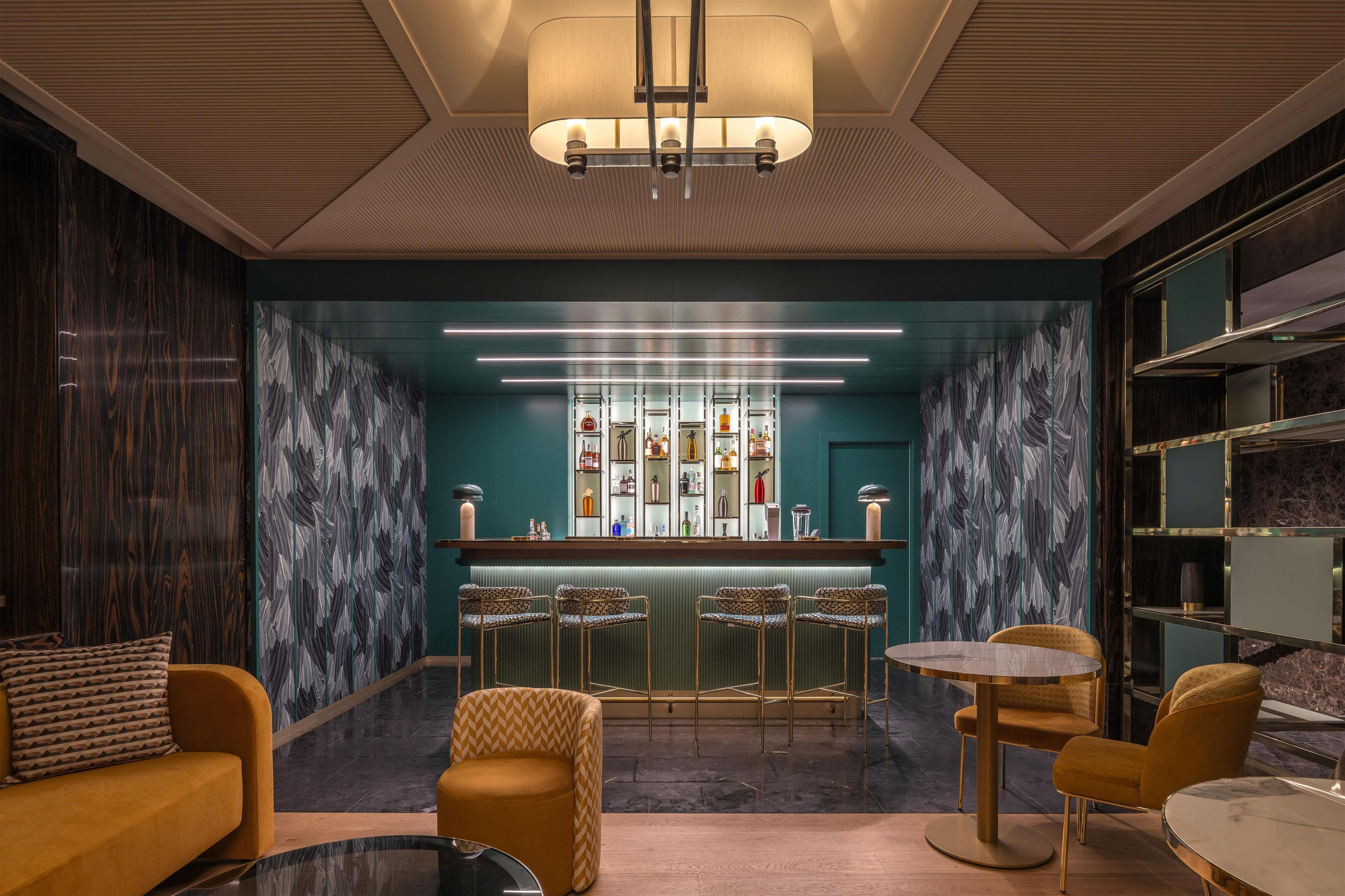 A modern bar area with a bar counter, seating, and a patterned wall.
