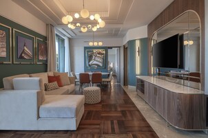 Un soggiorno moderno con divano, poggiapiedi e zona pranzo con sedie e tavolo.
