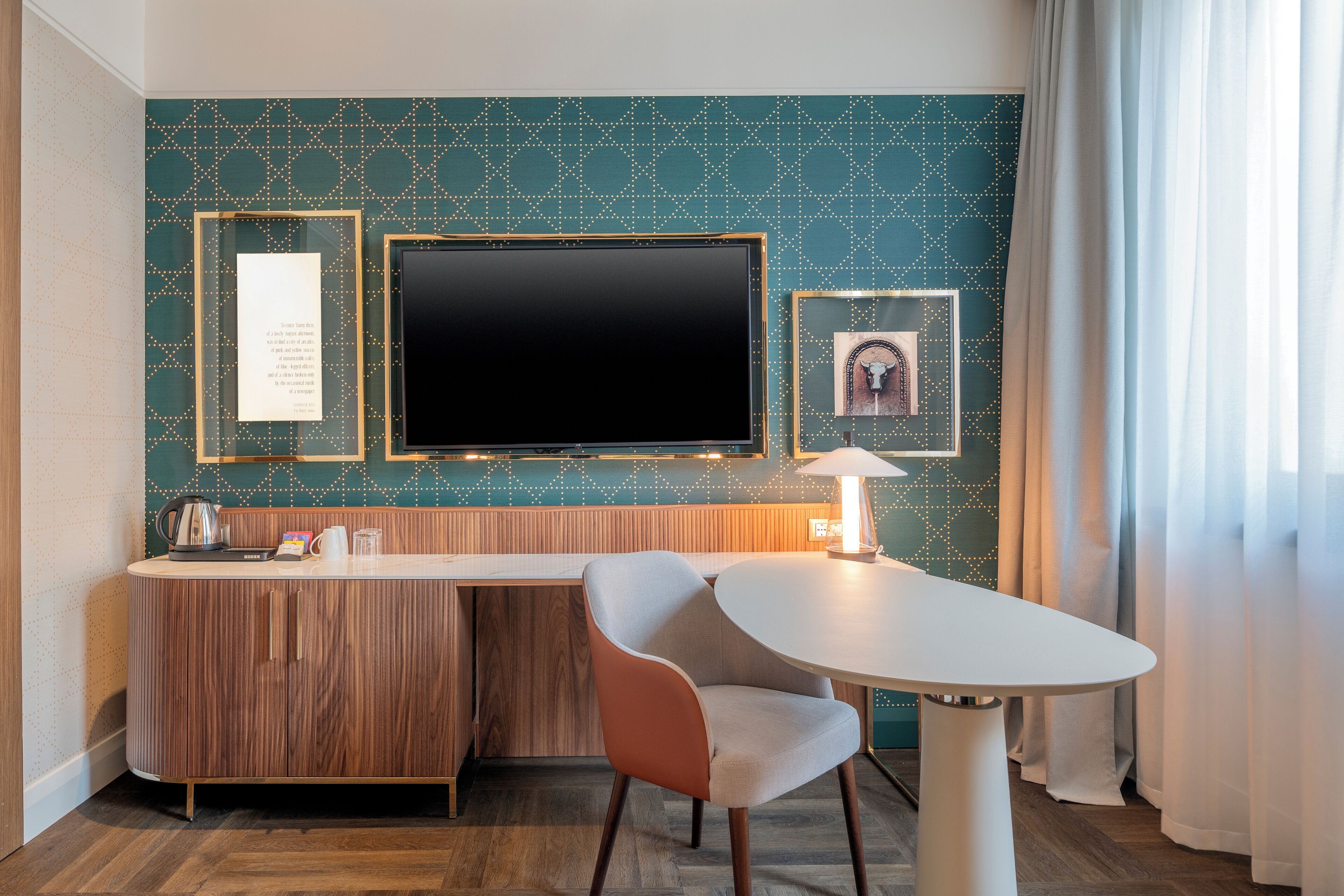 Hotelkamer met een houten kast, een flatscreen televisie, een tafeltje, een stoel en een decoratieve wand met ingelijste foto's.