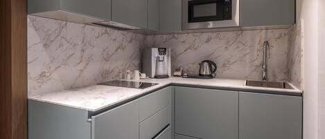 A compact kitchen with a built-in microwave, a coffee machine, and a sink.