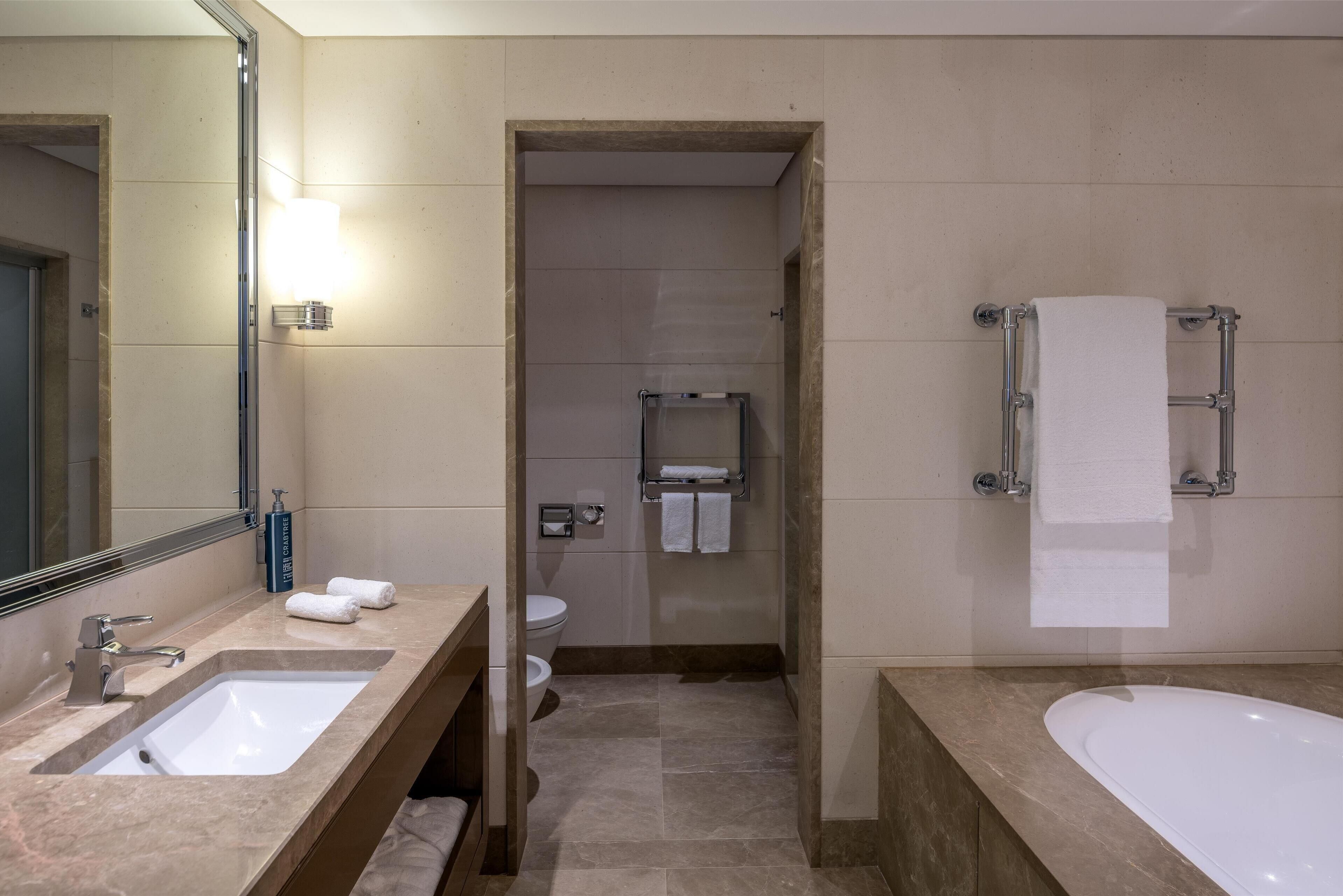 A modern bathroom with a sink, mirror, and bathtub.
