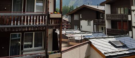 A traditional chalet-style building with balconies, a wooden facade, and a mountain backdrop.