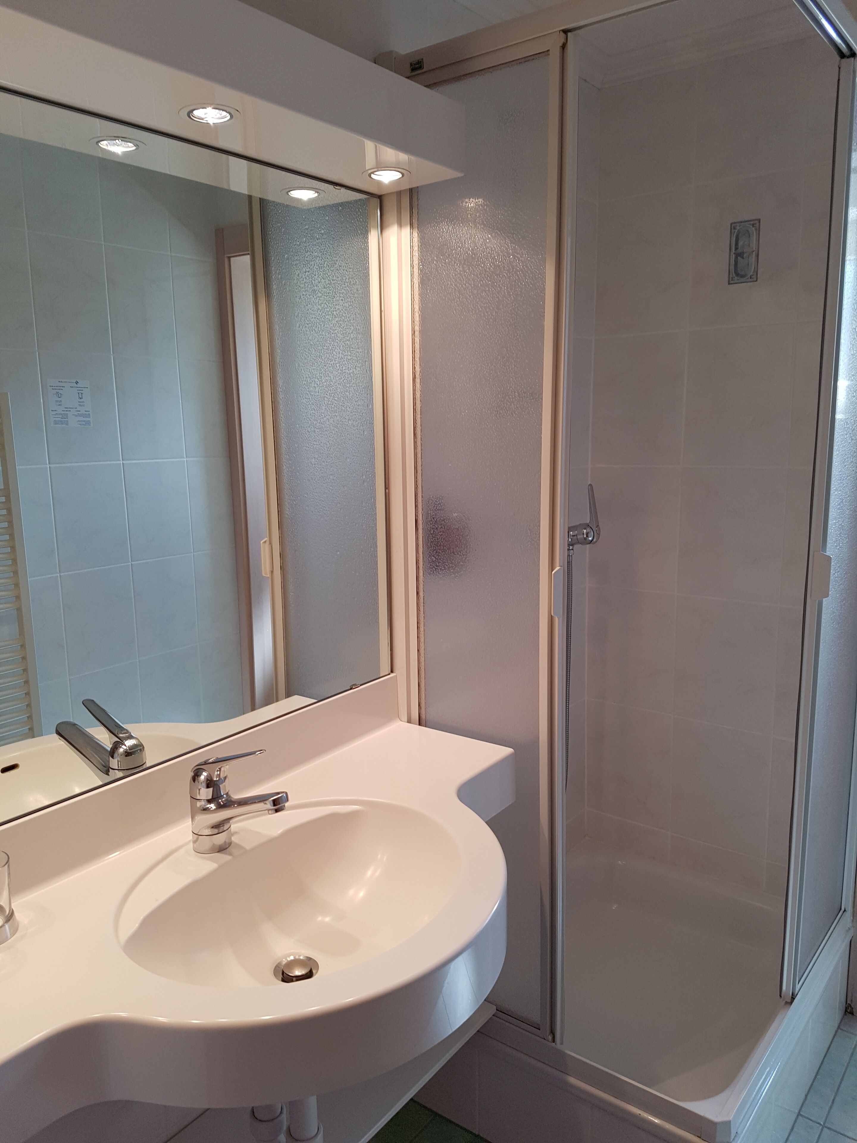 A bathroom with a white sink, a mirror, and a glass-enclosed shower.