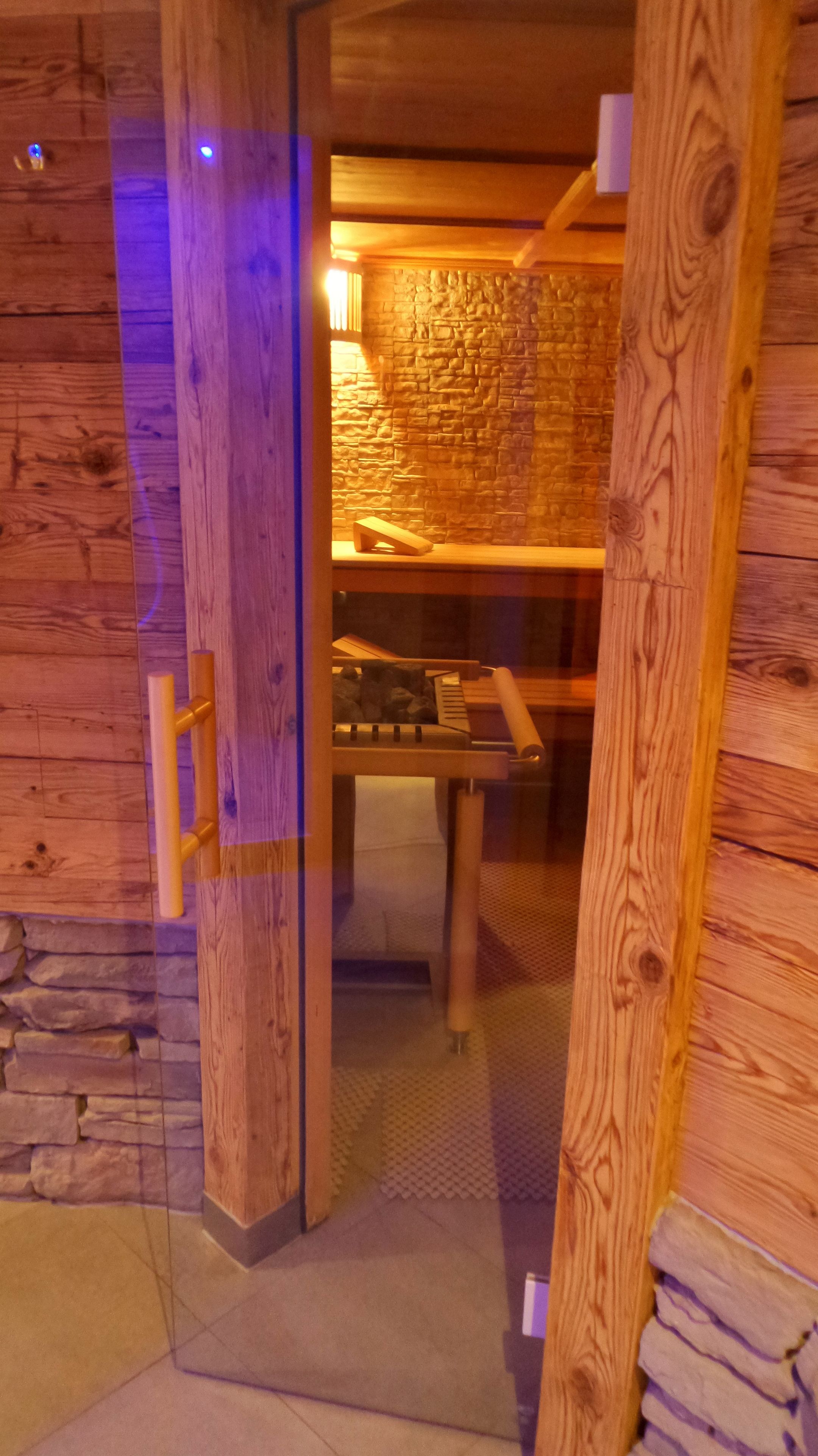 Un intérieur en bois avec un mur en pierre, une porte en bois et un banc sur lequel est posée une serviette.