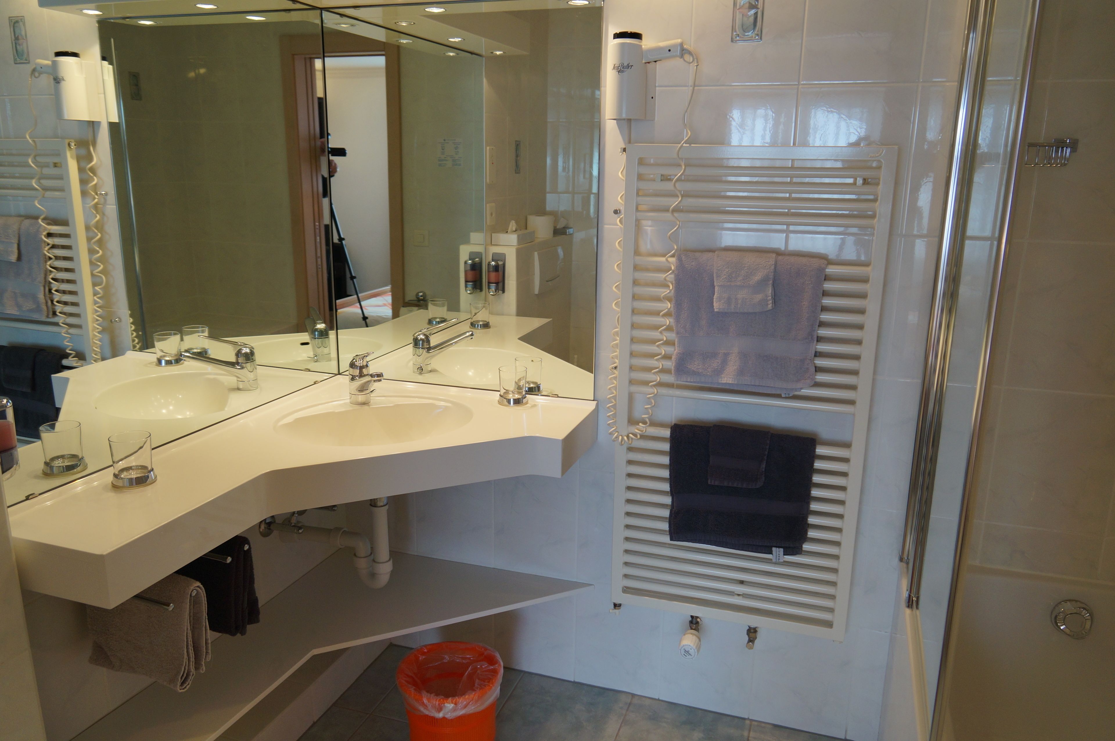A modern bathroom with dual sinks, a large mirror, and a towel rack.