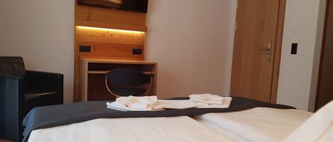 Quarto de hotel com cama, escrivaninha, cadeira e guarda-roupa.