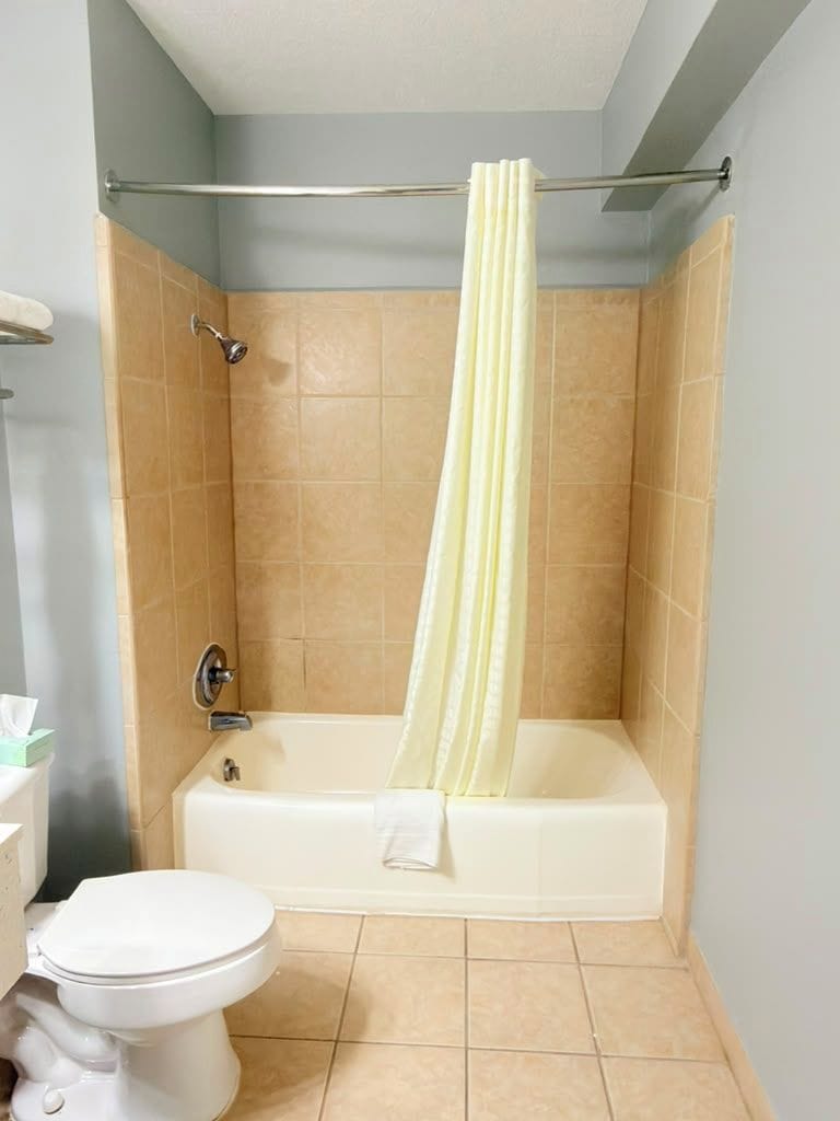 Un baño con bañera, inodoro y cortina de ducha.
