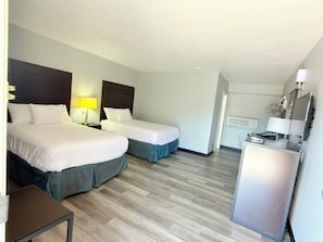 A hotel room with two beds, a desk, and a minibar.