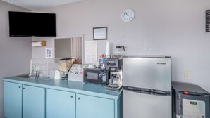 Eine Küchenzeile mit Mikrowelle, Kaffeemaschine und Kühlschrank.