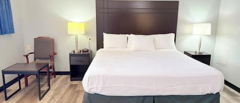 A hotel room with a large bed, two bedside tables with lamps, a small desk, and a chair.