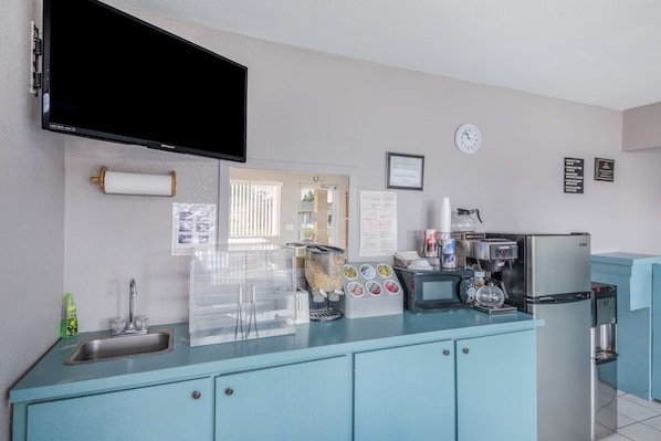 Una kitchenette equipada con un lavamanos, una cafetera, un microondas y un refrigerador.