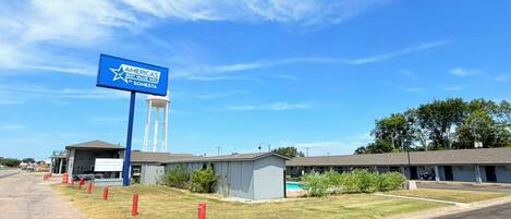 Un hotel con un letrero azul grande, una torre de agua y un estacionamiento.