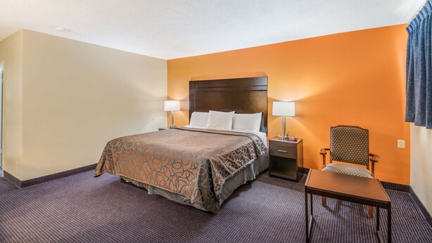 Ein Hotelzimmer mit Bett, Nachttischen, einem Sessel und einem kleinen Tisch.
