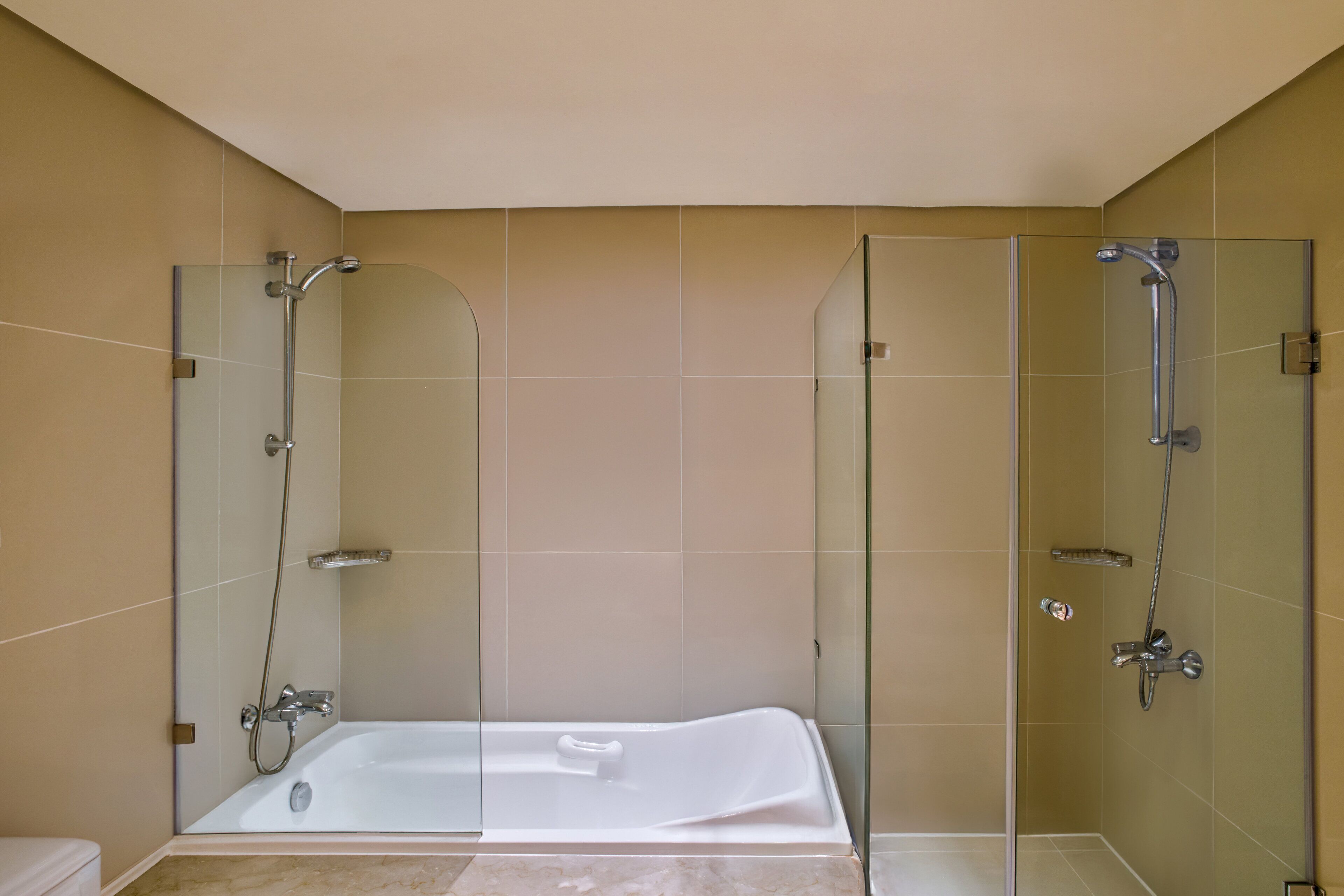 A modern bathroom with a glass-enclosed shower, a standalone bathtub, and beige tiled walls.