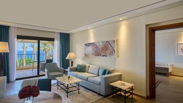 A modern hotel room with a balcony, a sofa, a coffee table, and a painting on the wall.