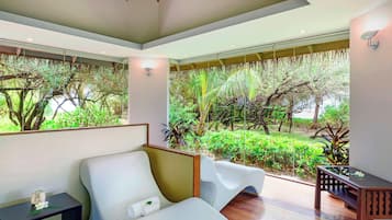 A modern room with a large window overlooking a lush garden. There is a white sofa and a small table with a decorative item.