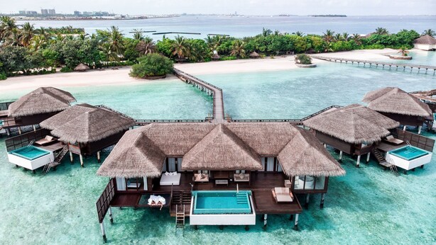 An overwater bungalows with thatched roofs, a central pool, and a pier connecting to the mainland. - Sheraton Maldives Full Moon Resort & Spa (Furanafushi Island)
