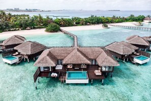 An overwater bungalows with thatched roofs, a central pool, and a pier connecting to the mainland. - Sheraton Maldives Full Moon Resort & Spa (Furanafushi Island)