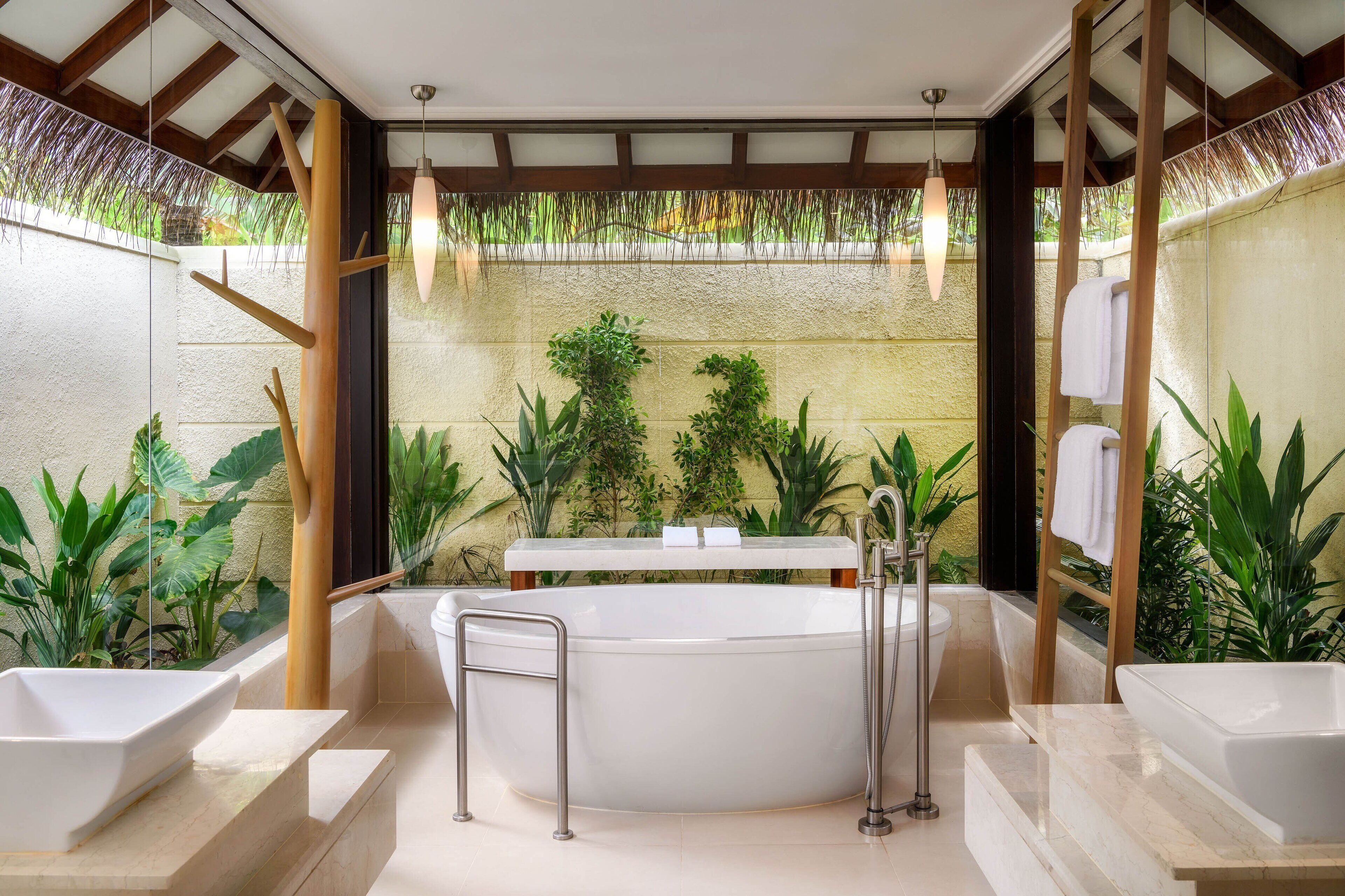 Un baño moderno con una bañera independiente, dos lavamanos y un espejo grande.