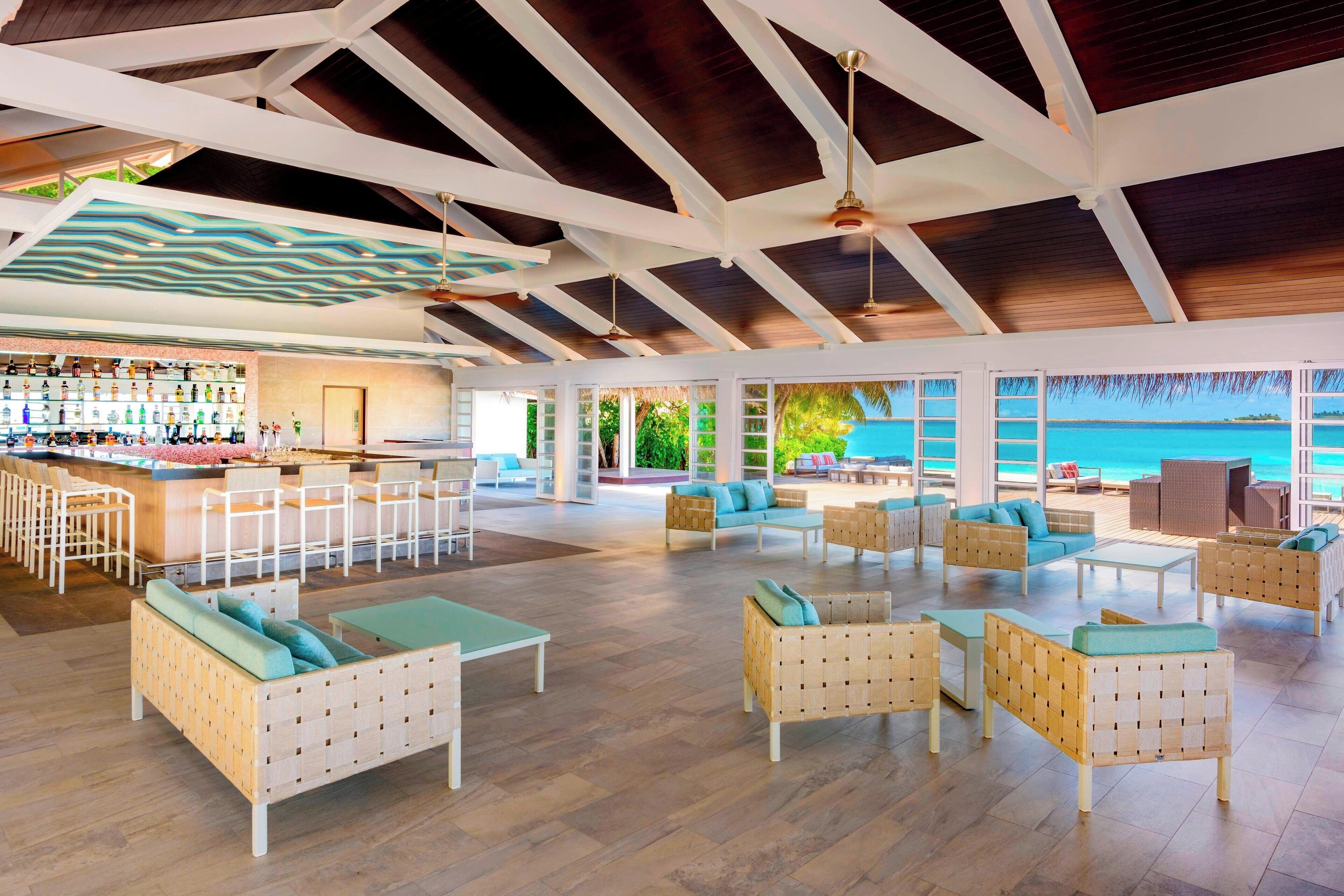 A spacious lounge area with multiple seating options, a bar, and a view of the ocean.