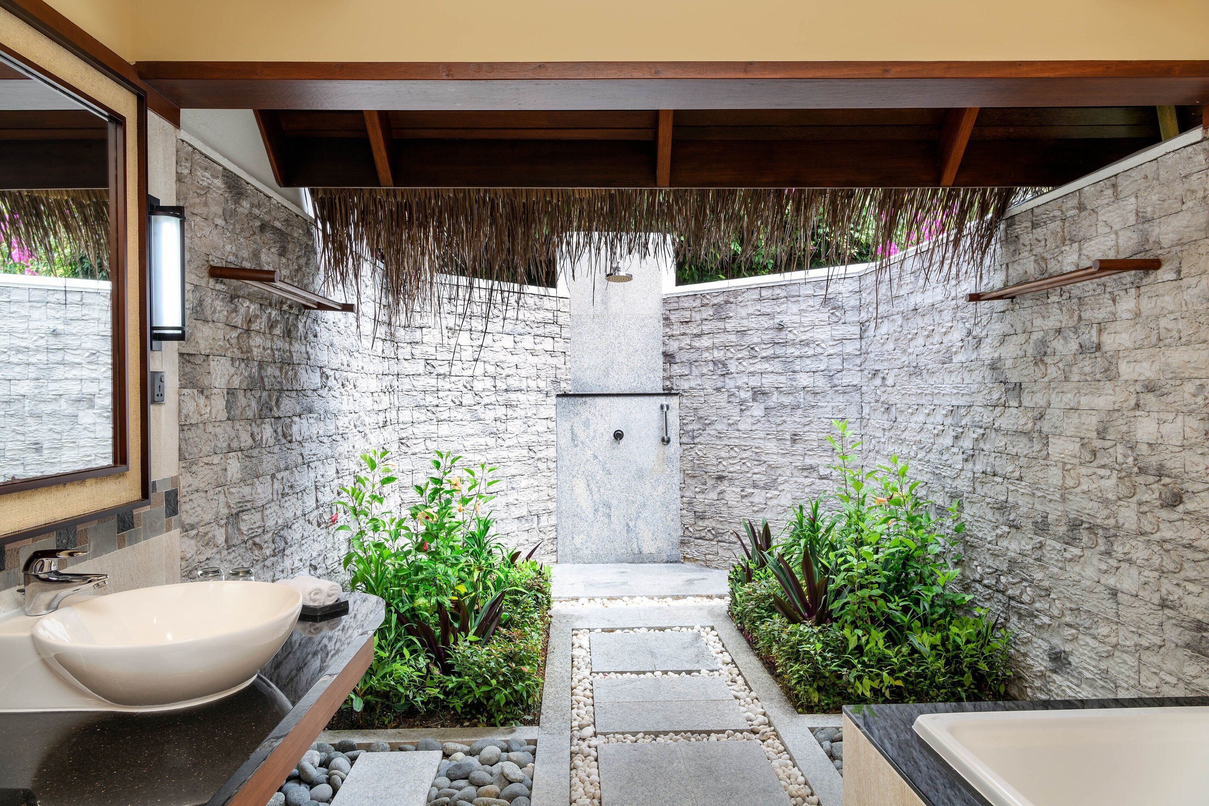 Un baño moderno con pared de piedra, un lavamanos grande y una zona de ducha.
