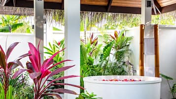 A spa area with a white bathtub surrounded by lush tropical plants.