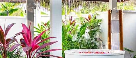 A spa area with a white bathtub surrounded by lush tropical plants.