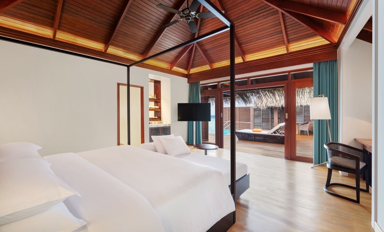 Un dormitorio amplio con una cama grande, televisor y vistas a una piscina y zona de estar.