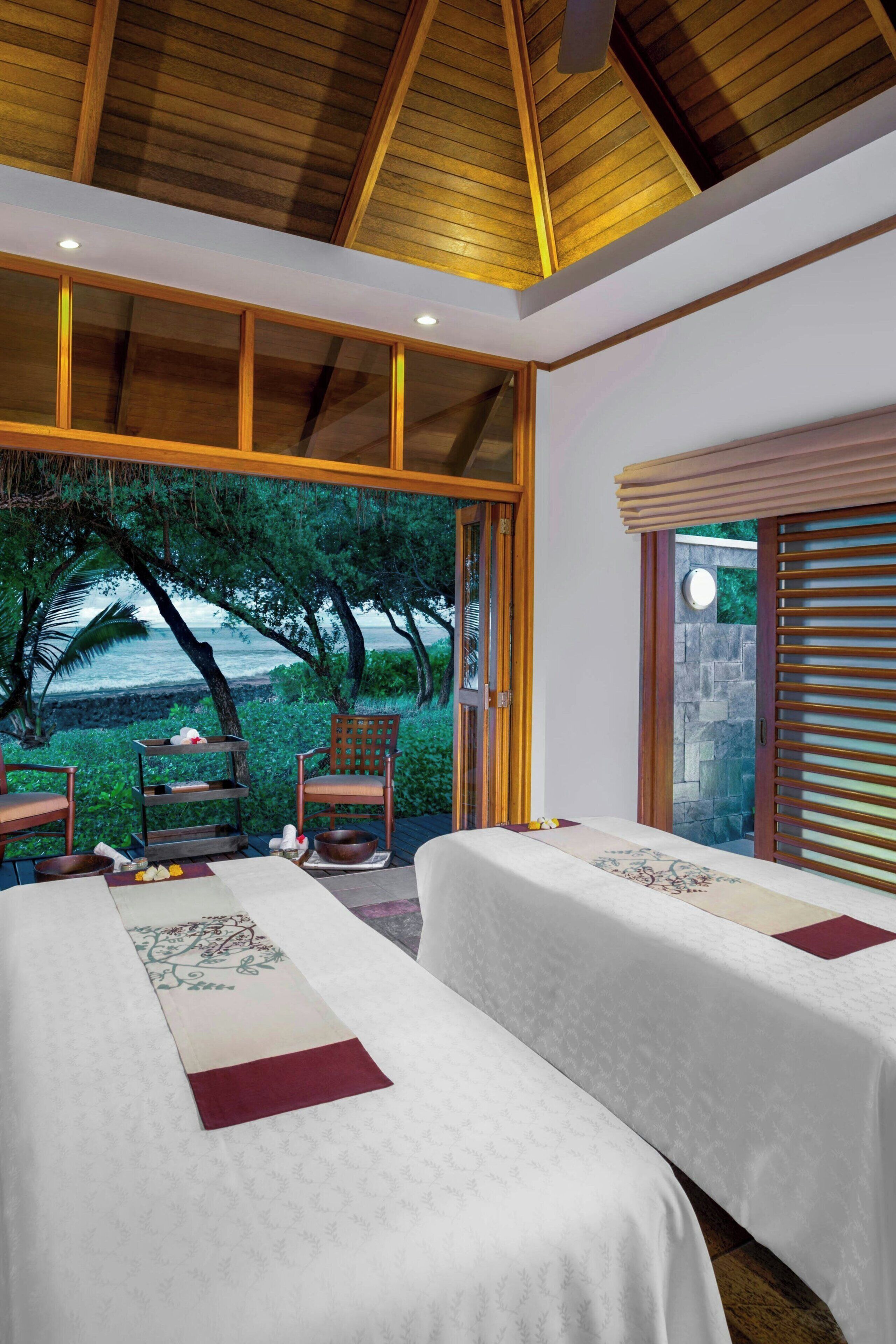 Ein Zimmer mit zwei Betten, einer Holzbalkendecke und Meerblick.