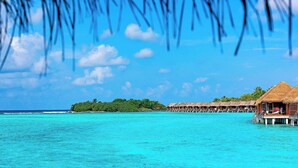 Overwater bungalows with thatched roofs and wooden walkways extending into turquoise waters. - Sheraton Maldives Full Moon Resort & Spa (Furanafushi Island)