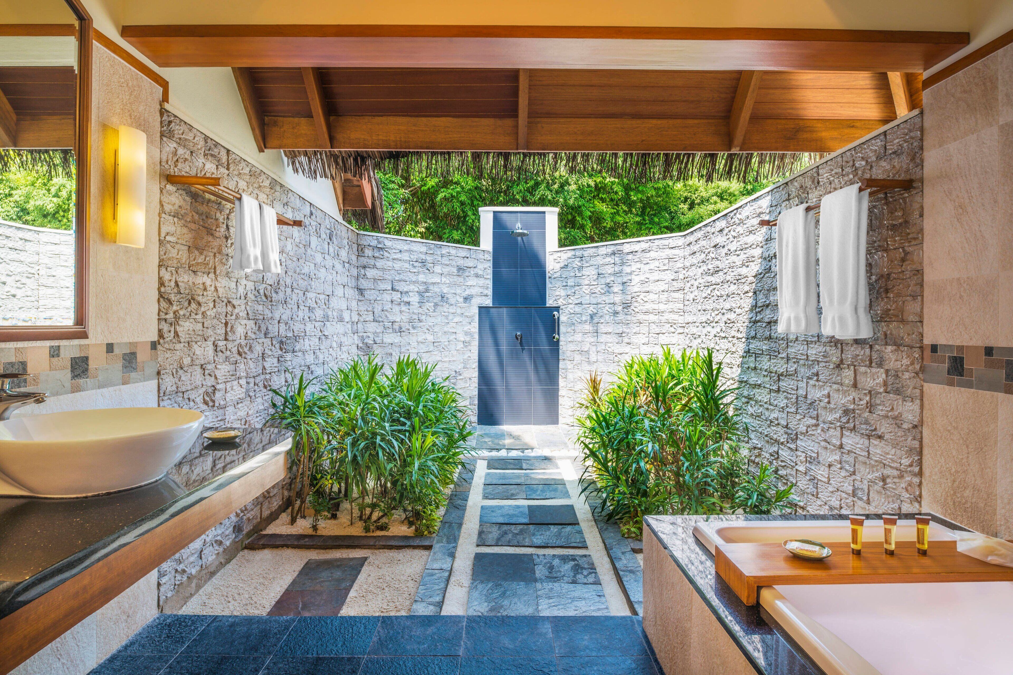 A modern bathroom with a stone wall, a large sink, a bathtub, and a shower.