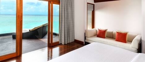 Un dormitorio con una cama grande, un sofá y vista al océano.