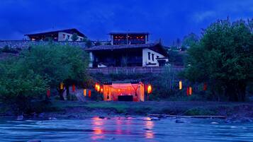Un hotel a orillas del río con varias edificaciones, una zona con carpas y vistas al río.