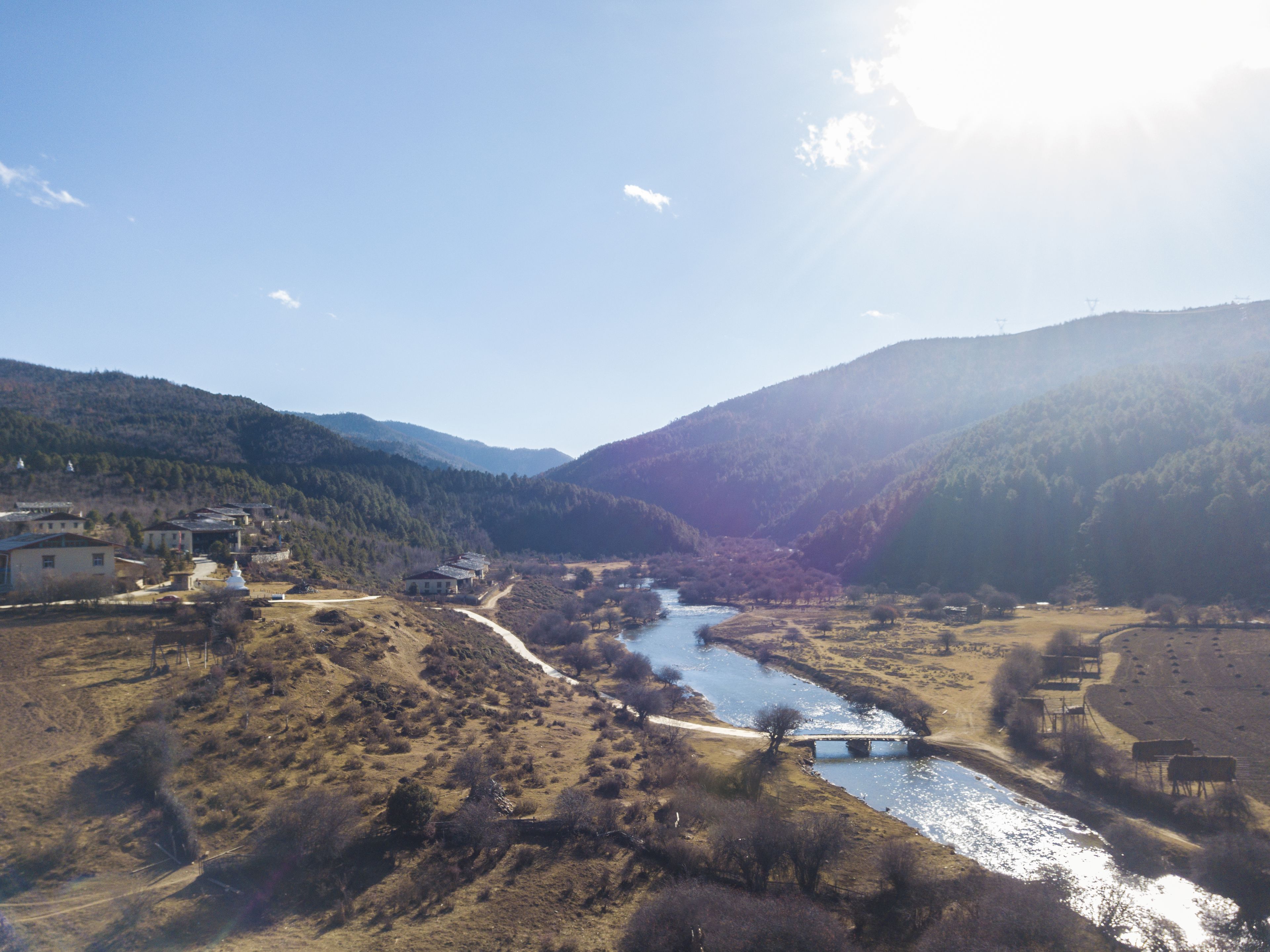 A rural landscape with a river, a bridge, and buildings on the hillsides.