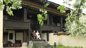 A traditional building with a wooden staircase leading to a porch with seating. - Banyan Tree Ringha (Deqin)