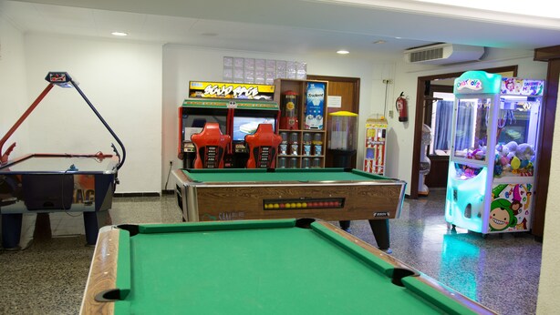 Een pooltafel met een rood en zwart biljartkeu, een biljartspel en een grijpmachine.