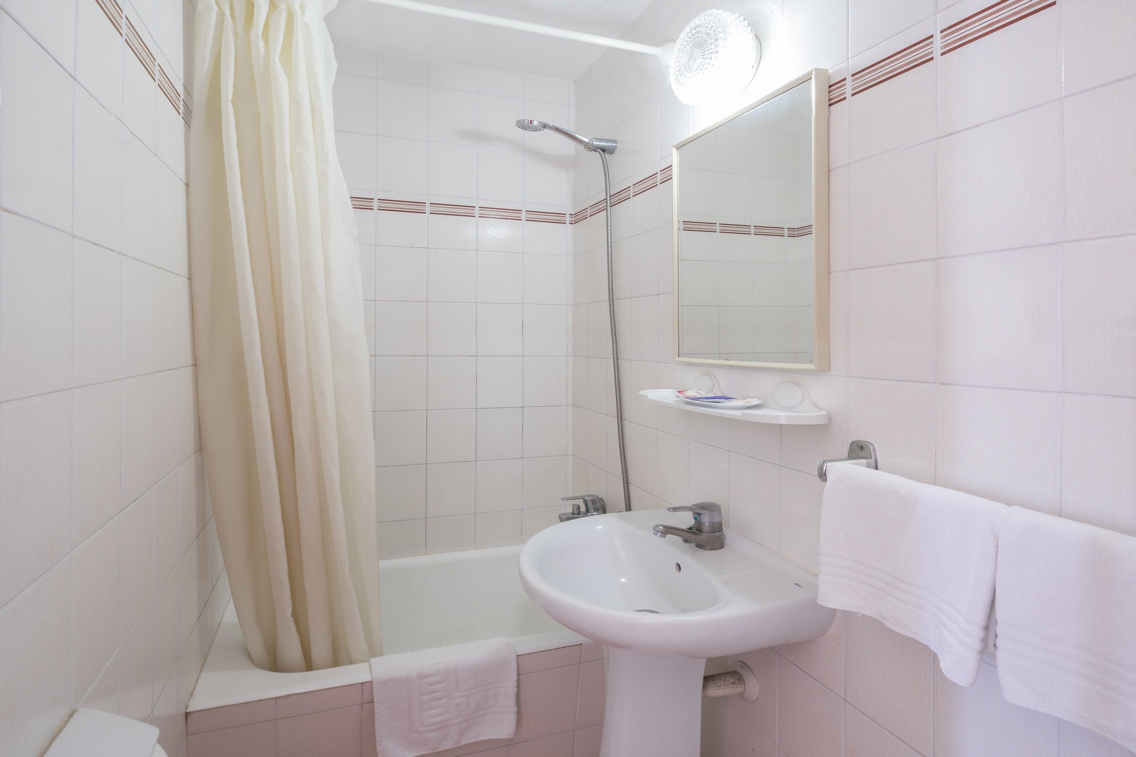 A bathroom with a bathtub, a sink, a mirror, and a towel rack.