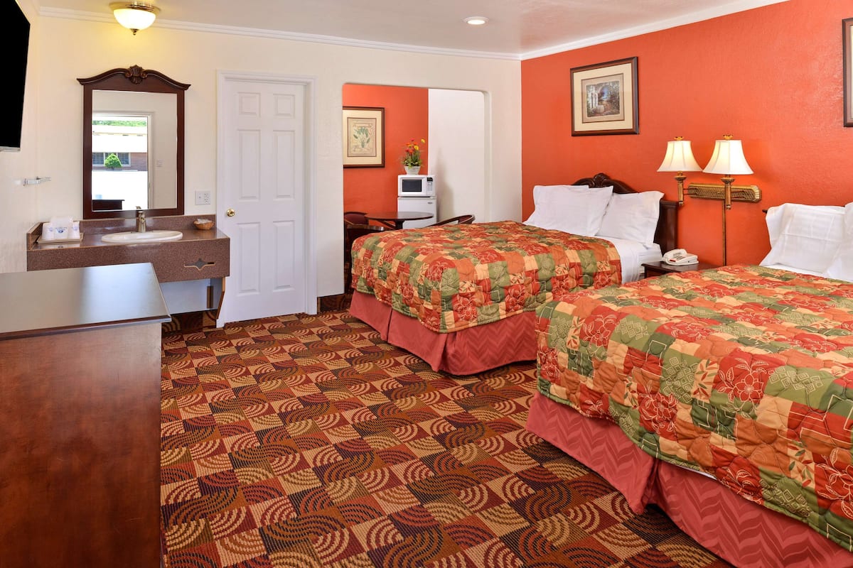 A hotel room with a bed, a desk, a chair, a microwave, and a bathroom.
