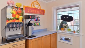 A coffee bar with a juice dispenser, a coffee machine, and a window with a view of the street.