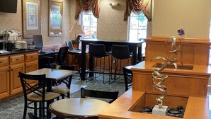 A restaurant with wooden furniture, a bar area, and a counter with a decorative metal piece. - SureStay Plus Hotel by Best Western Warner Robins AFB (Warner Robins)