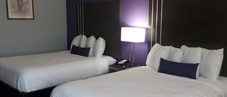 Dos camas individuales con sábanas blancas y cabeceros oscuros en una habitación de hotel.