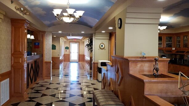 A hotel lobby with a checkered floor, wooden paneling, a chandelier, and a view of the exit. - SureStay Plus Hotel by Best Western Warner Robins AFB (Warner Robins)