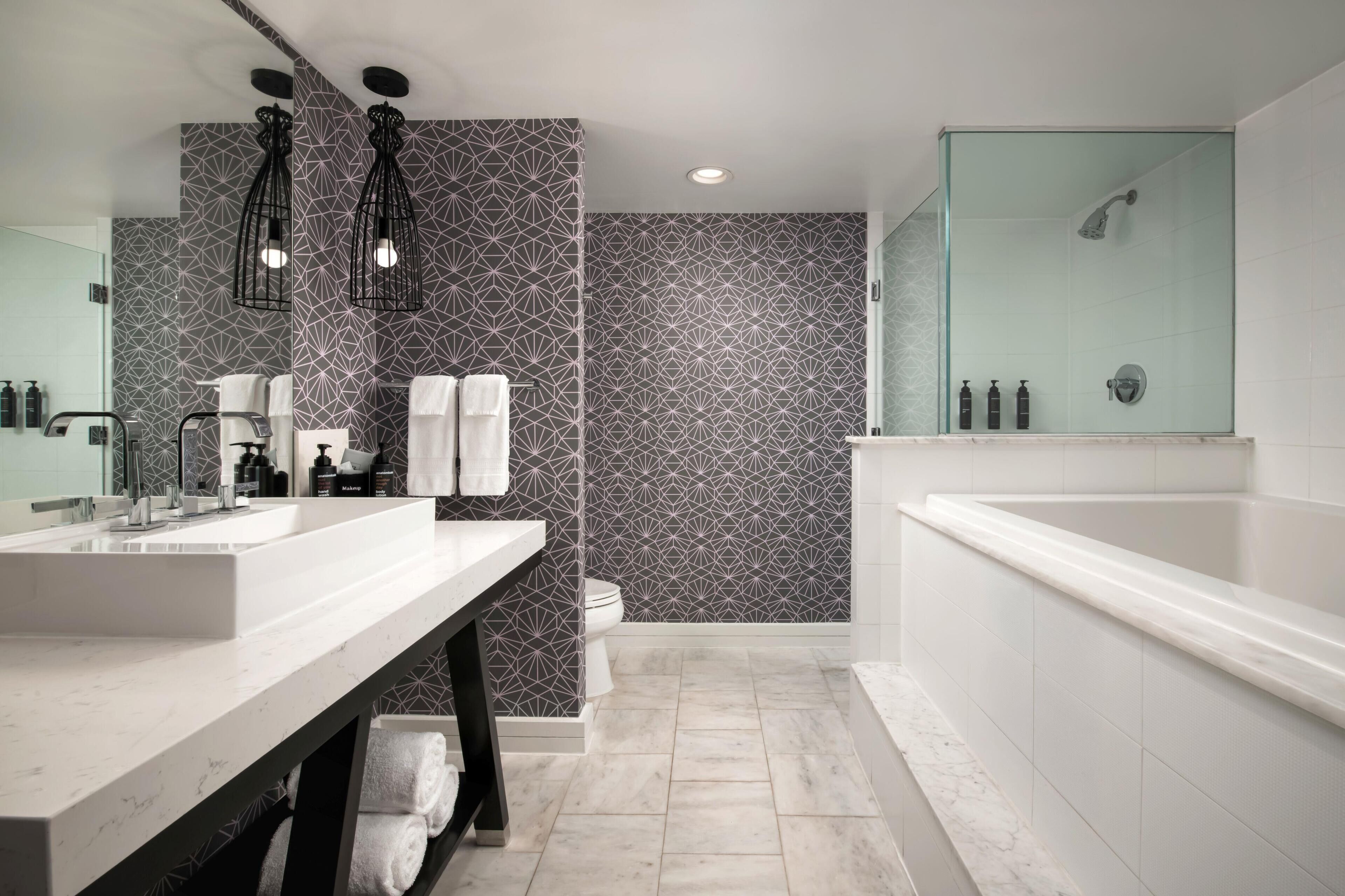 A modern bathroom with a large mirror, two sinks, a toilet, and a glass-enclosed shower.